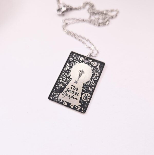 Secret Garden Book Necklace – Engraved Miniature Book Pendant – Literary Jewelry Gift 4 Secret Garden miniature book pendant — mirror-polish stainless steel, engraved in-house. Cottagecore literary gift for the book lover, gardener, or dreamer. “If you look the right way, you can see that the whole world is a garden.” 🌿🗝️ Unlock a bit of magic with our Secret Garden Book Necklace. A tribute to Frances Hodgson Burnett’s beloved tale of hidden beauty and second chances, this pendant is designed for the dreamers who believe in the power of growth. Whether you’re a lifelong reader or a (4)