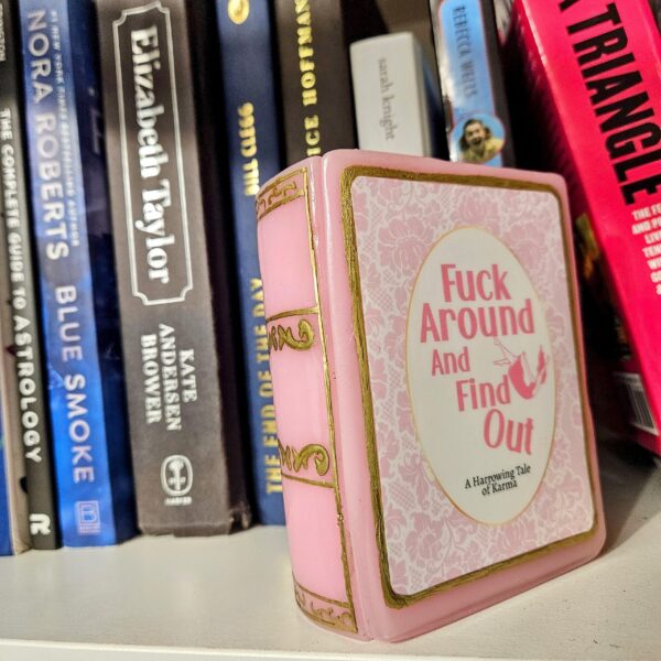 Resin Book Box: 'Fuck Around and Find Out - Handcrafted Storage for Book Lovers 2 Hide your treasures in plain sight with this handmade resin book box—a sassy and stylish storage solution for any book lover! Designed to blend seamlessly into your bookshelf or desk, this epoxy resin book box is both functional and eye-catching. ✨ Features: 📖 Handcrafted with high-quality tinted epoxy resin – durable, glossy, and built to last. 🎨 Hand-painted page details – complete with gold accents on the edges and spine for that luxury book aesthetic. 💖 Custom-designed cover – featuring a pi (2)