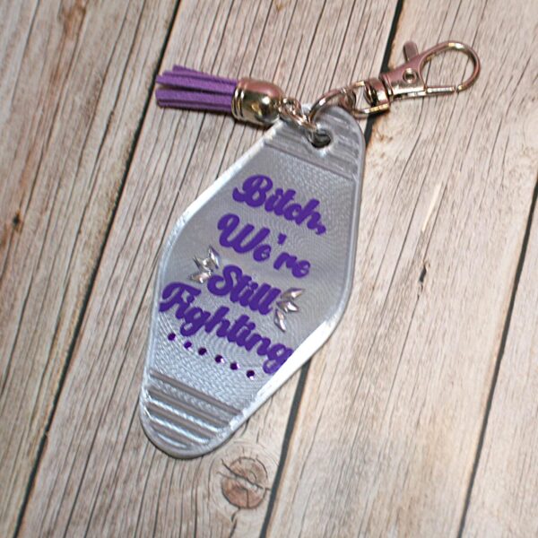 il_fullxfull.7629583103_9s11 Protest Motel Keychain - Bitch, We’re Still Fighting Keychain