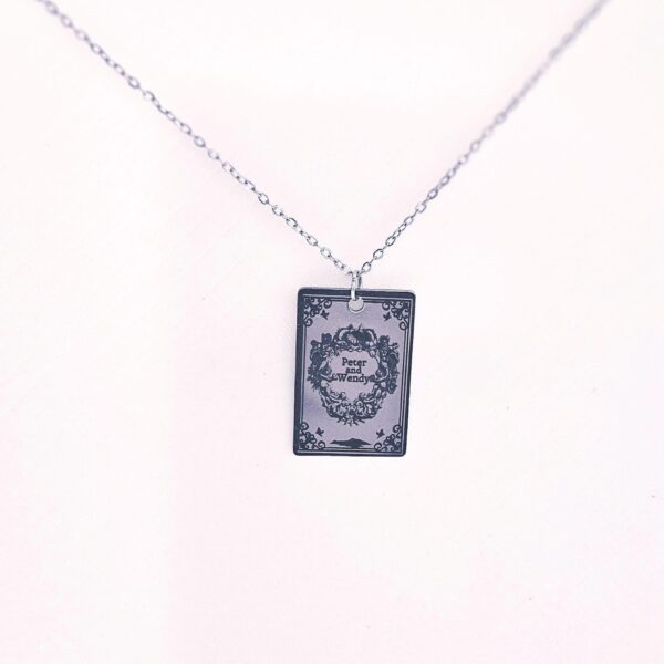 Engraved Peter and Wendy Book Necklace – Stainless Steel Literary Jewelry 5 Miniature Peter and Wendy book pendant, engraved in-house with original cover art. Mirror-polish stainless steel, tarnish-proof. A gift for every lost girl. “To live would be an awfully big adventure.” ✨🧚♂️ Fly away to Neverland with a piece of jewelry as unique as the story itself. Our Peter and Wendy Book Necklace features original cover art designed in our studio, making this a one-of-a-kind tribute you won't find anywhere else. Forget mass-produced charms. Each pendant is engraved in-house (5)