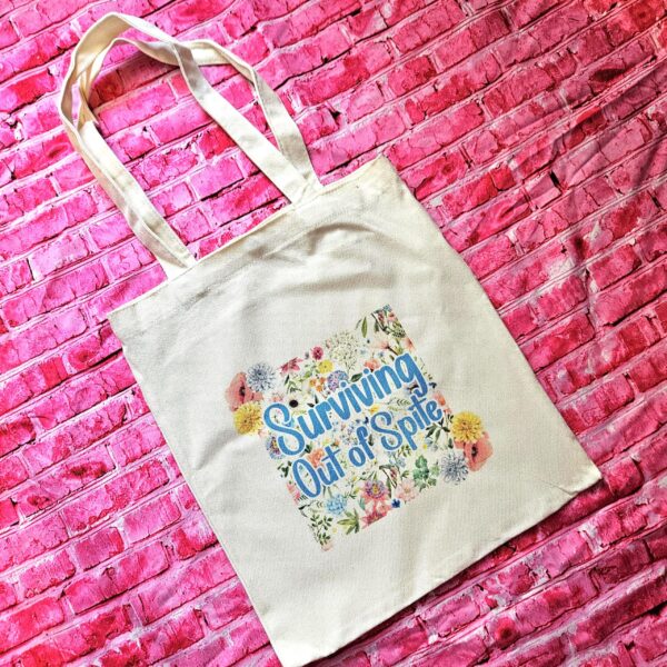 For the fiercely independent friend who thrives on proving people wrong! 💐 Give the gift of unapologetic resilience with this Surviving Out of Spite tote bag. Why this tote stands on business: 💼 Permanent Design: The design is sublimated. The ink is dyed directly into the fibers, meaning it won’t fade, rub off, or lose its punch—no matter how many times you wash it. 🧼✨ Premium Build: Made from high-quality, medium-weight cotton canvas. It’s sturdy enough for your laptop, your protest signs, or a (5)
