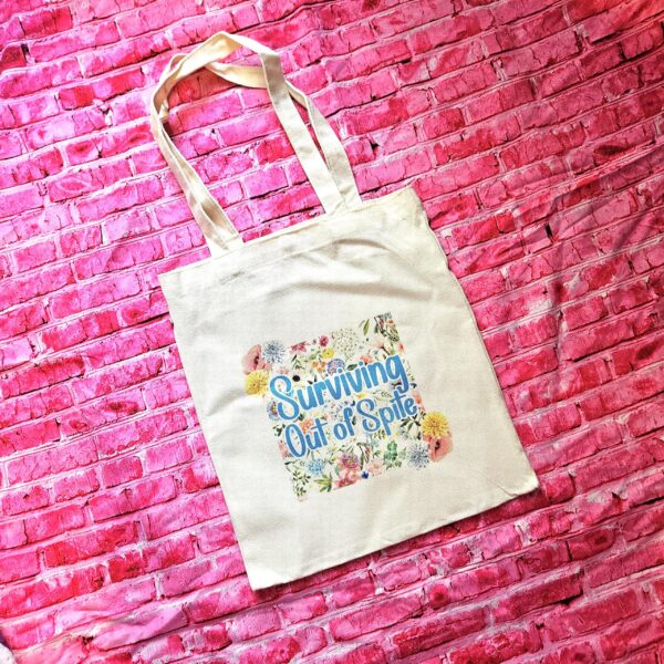 For the fiercely independent friend who thrives on proving people wrong! 💐 Give the gift of unapologetic resilience with this Surviving Out of Spite tote bag. Why this tote stands on business: 💼 Permanent Design: The design is sublimated. The ink is dyed directly into the fibers, meaning it won’t fade, rub off, or lose its punch—no matter how many times you wash it. 🧼✨ Premium Build: Made from high-quality, medium-weight cotton canvas. It’s sturdy enough for your laptop, your protest signs, or a (6)