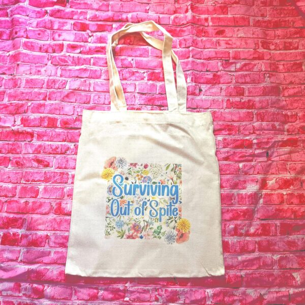 For the fiercely independent friend who thrives on proving people wrong! 💐 Give the gift of unapologetic resilience with this Surviving Out of Spite tote bag. Why this tote stands on business: 💼 Permanent Design: The design is sublimated. The ink is dyed directly into the fibers, meaning it won’t fade, rub off, or lose its punch—no matter how many times you wash it. 🧼✨ Premium Build: Made from high-quality, medium-weight cotton canvas. It’s sturdy enough for your laptop, your protest signs, or a (2)