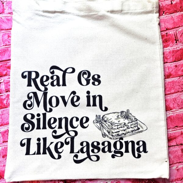 Lasagna Quote Tote Bag, Funny Hip Hop Lyric Gift, Canvas Bag With Pocket 3 The perfect gift for the hip-hop fan or anyone who makes moves in silence! 🤫 Featuring the iconic "Real G's Move In Silence Like Lasagna" lyric, this premium sublimated tote bag is as functional as it is funny. Why this tote stands on business: 💼 Permanent, Vibrant Art: We use sublimation, meaning the ink is dyed directly into the cotton canvas fibers. It’s smooth to the touch and will never fade, peel, or rub off. 🧼✨ Premium Construction: Made from high-quality, medium-weight cotton canvas. It’ (3)
