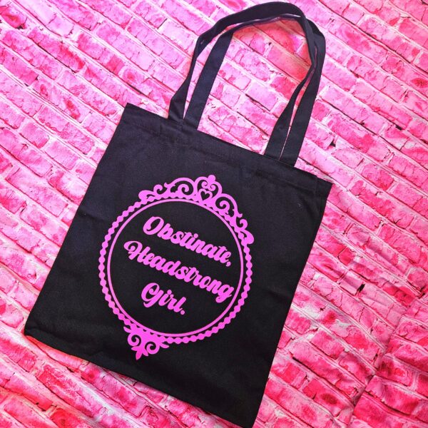 Jane Austen Tote Bag - Obstinate Headstrong Girl Canvas Book Bag 5 The ultimate gift for the witty bookworm! 📚 This bold Jane Austen tote bag features the "Obstinate Headstrong Girl" quote. Perfect for library hauls and gifts. Obsessed with Jane Austen but tired of boring, beige book bags? We’ve got you. This She’sSoCrafty Goods original design takes the wit of Pride and Prejudice and gives it a bold, modern glow-up. 💖✨ Crafted from premium, heavyweight black cotton canvas, this 14" x 15" tote is sturdy enough to carry your entire TBR (To-Be-Read) pile, your la (5)