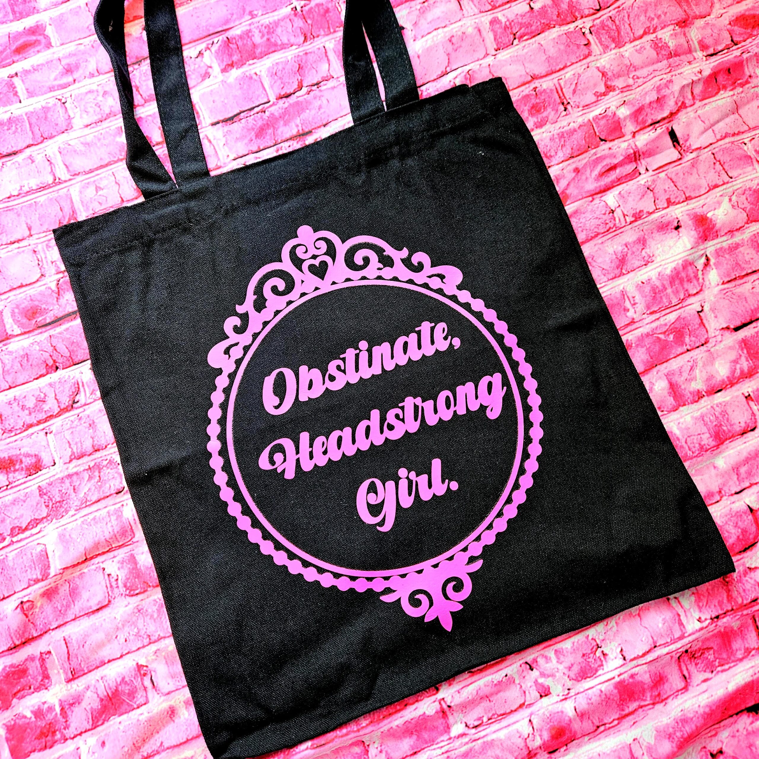 The ultimate gift for the witty bookworm! 📚 This bold Jane Austen tote bag features the "Obstinate Headstrong Girl" quote. Perfect for library hauls and gifts. Obsessed with Jane Austen but tired of boring, beige book bags? We’ve got you. This She’sSoCrafty Goods original design takes the wit of Pride and Prejudice and gives it a bold, modern glow-up. 💖✨ Crafted from premium, heavyweight black cotton canvas, this 14" x 15" tote is sturdy enough to carry your entire TBR (To-Be-Read) pile, your la (3)