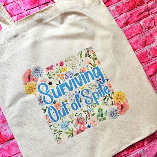For the fiercely independent friend who thrives on proving people wrong! 💐 Give the gift of unapologetic resilience with this Surviving Out of Spite tote bag. Why this tote stands on business: 💼 Permanent Design: The design is sublimated. The ink is dyed directly into the fibers, meaning it won’t fade, rub off, or lose its punch—no matter how many times you wash it. 🧼✨ Premium Build: Made from high-quality, medium-weight cotton canvas. It’s sturdy enough for your laptop, your protest signs, or a (7)