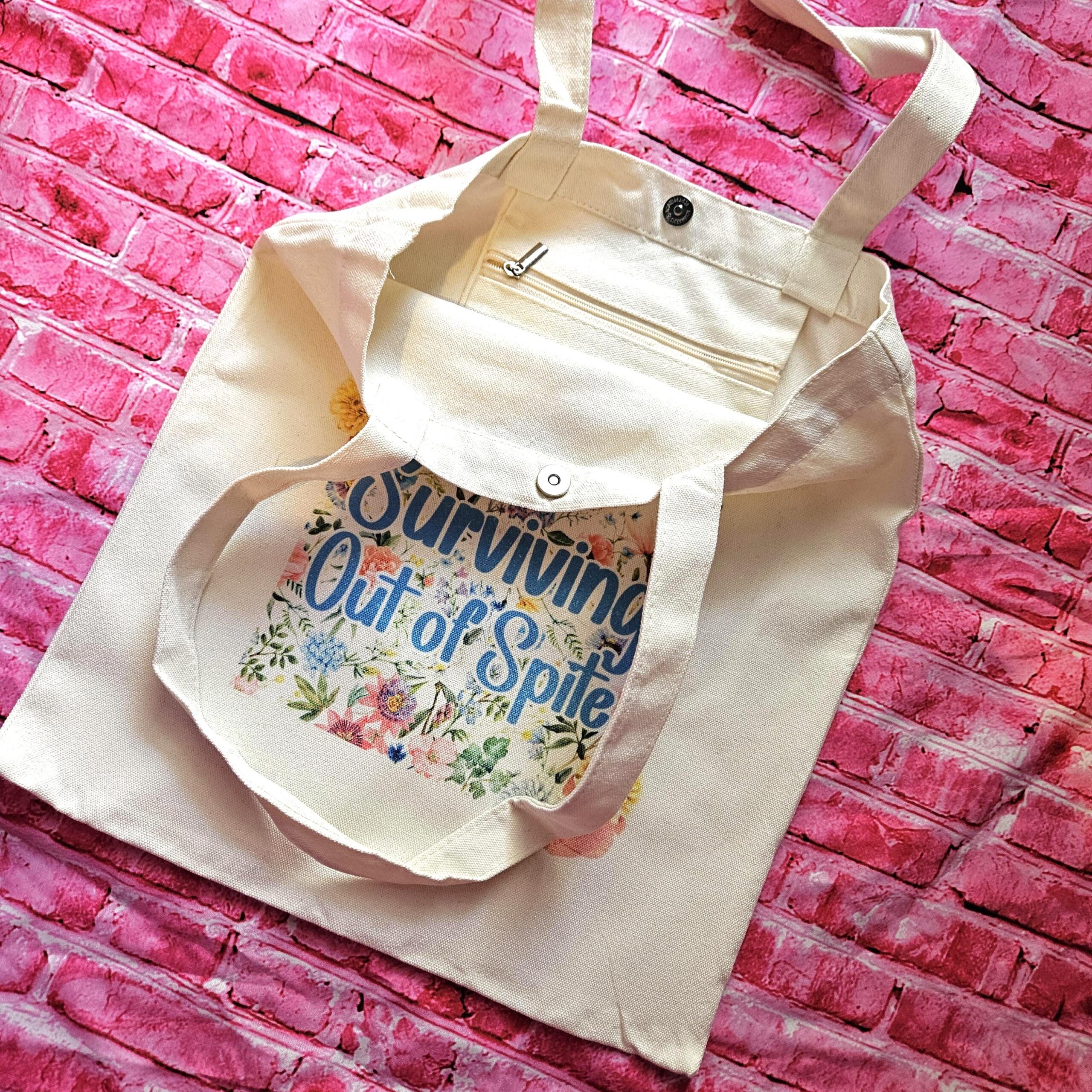 For the fiercely independent friend who thrives on proving people wrong! 💐 Give the gift of unapologetic resilience with this Surviving Out of Spite tote bag. Why this tote stands on business: 💼 Permanent Design: The design is sublimated. The ink is dyed directly into the fibers, meaning it won’t fade, rub off, or lose its punch—no matter how many times you wash it. 🧼✨ Premium Build: Made from high-quality, medium-weight cotton canvas. It’s sturdy enough for your laptop, your protest signs, or a (8)