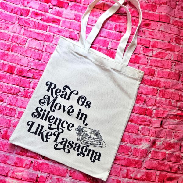 Lasagna Quote Tote Bag, Funny Hip Hop Lyric Gift, Canvas Bag With Pocket 1 The perfect gift for the hip-hop fan or anyone who makes moves in silence! 🤫 Featuring the iconic "Real G's Move In Silence Like Lasagna" lyric, this premium sublimated tote bag is as functional as it is funny. Why this tote stands on business: 💼 Permanent, Vibrant Art: We use sublimation, meaning the ink is dyed directly into the cotton canvas fibers. It’s smooth to the touch and will never fade, peel, or rub off. 🧼✨ Premium Construction: Made from high-quality, medium-weight cotton canvas. It’ (1)