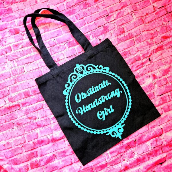 Jane Austen Tote Bag - Obstinate Headstrong Girl Canvas Book Bag 6 The ultimate gift for the witty bookworm! 📚 This bold Jane Austen tote bag features the "Obstinate Headstrong Girl" quote. Perfect for library hauls and gifts. Obsessed with Jane Austen but tired of boring, beige book bags? We’ve got you. This She’sSoCrafty Goods original design takes the wit of Pride and Prejudice and gives it a bold, modern glow-up. 💖✨ Crafted from premium, heavyweight black cotton canvas, this 14" x 15" tote is sturdy enough to carry your entire TBR (To-Be-Read) pile, your la (6)
