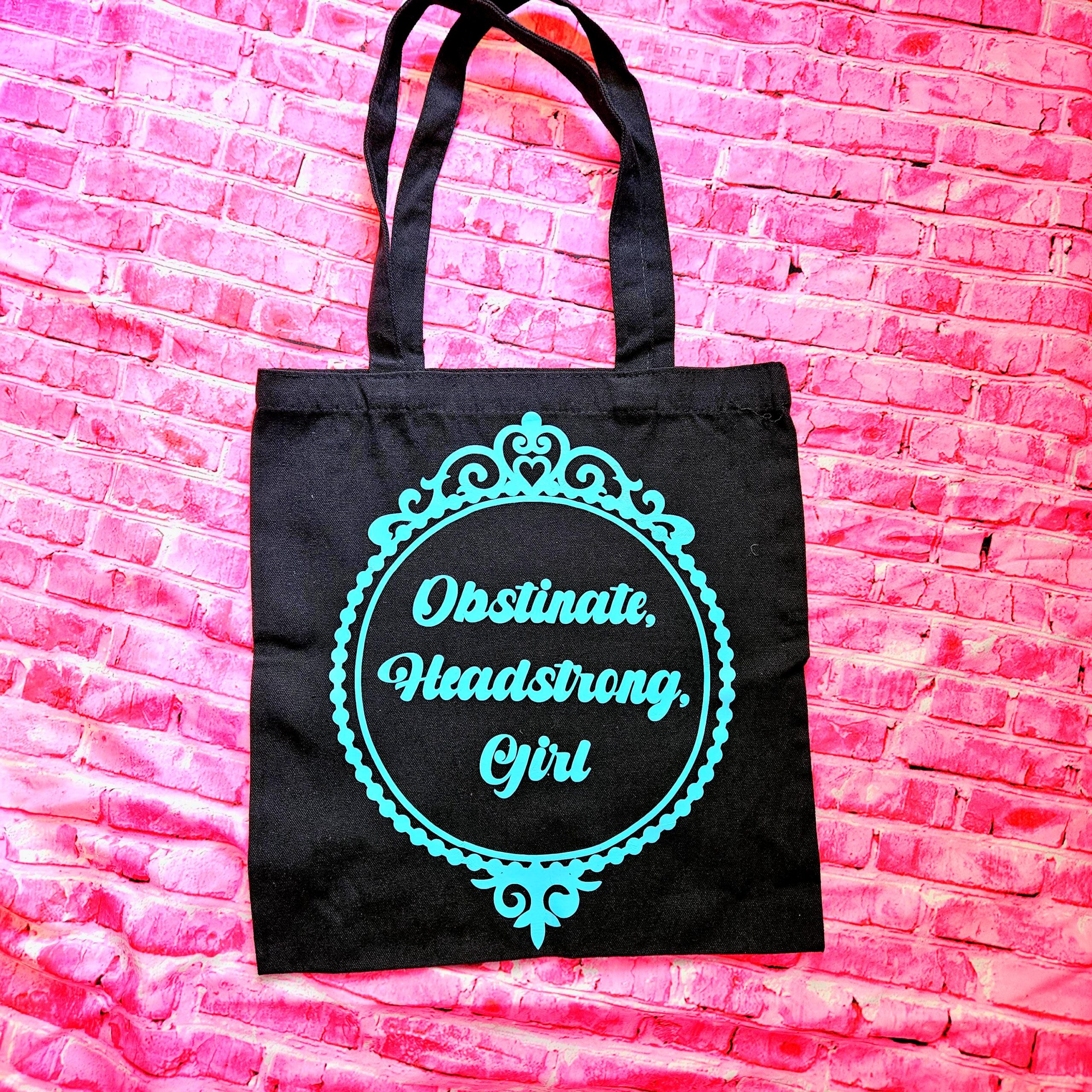 The ultimate gift for the witty bookworm! 📚 This bold Jane Austen tote bag features the "Obstinate Headstrong Girl" quote. Perfect for library hauls and gifts. Obsessed with Jane Austen but tired of boring, beige book bags? We’ve got you. This She’sSoCrafty Goods original design takes the wit of Pride and Prejudice and gives it a bold, modern glow-up. 💖✨ Crafted from premium, heavyweight black cotton canvas, this 14" x 15" tote is sturdy enough to carry your entire TBR (To-Be-Read) pile, your la (7)