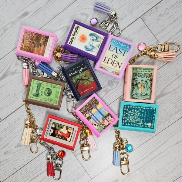 Custom Mini Book Bag Charm, Bookish Keychain, Personalized Reader Gift 2 Your accessories should speak as loudly as you do. This custom mini book bag charm is unlike anything else on Etsy — and I know that because I spent months designing it from scratch to make sure. Send me any book cover link. I'll turn it into a personalized bookish keychain you'll actually want on your bag every single day. THE DETAILS THAT MAKE THE DIFFERENCE ✦ Hand-painted metallic chrome "pages" — gold or silver, finished by hand on every single edge. That gilded look isn't a sticker. It isn' (2)