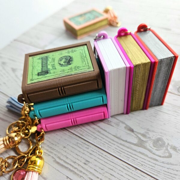 Custom Mini Book Bag Charm, Bookish Keychain, Personalized Reader Gift 15 Your accessories should speak as loudly as you do. This custom mini book bag charm is unlike anything else on Etsy — and I know that because I spent months designing it from scratch to make sure. Send me any book cover link. I'll turn it into a personalized bookish keychain you'll actually want on your bag every single day. THE DETAILS THAT MAKE THE DIFFERENCE ✦ Hand-painted metallic chrome "pages" — gold or silver, finished by hand on every single edge. That gilded look isn't a sticker. It isn' (15)