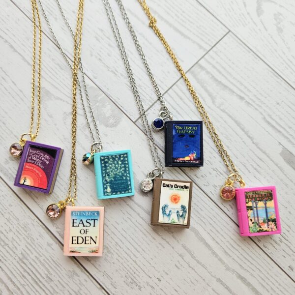 Custom Miniature Book Necklace, Personalized Book Lover Gift, Bookish Jewelry 1 Send us the link, we'll make it tiny. Your favorite book cover, shrunk to charm-sized perfection and hung around your neck. This custom miniature book necklace is a personalized book lover gift — handmade bookish jewelry featuring a 3D printed mini book pendant with hand-gilded pages and an 18" stainless steel chain. ✦ Pendant size: .85" H × .75" W ✦ Construction: 100% handmade and 3D printed from an original SSC design — never mass produced ✦ Cover: Printed from your chosen image, laminated for (1)