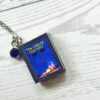 Custom Miniature Book Necklace, Personalized Book Lover Gift, Bookish Jewelry 8 Send us the link, we'll make it tiny. Your favorite book cover, shrunk to charm-sized perfection and hung around your neck. This custom miniature book necklace is a personalized book lover gift — handmade bookish jewelry featuring a 3D printed mini book pendant with hand-gilded pages and an 18" stainless steel chain. ✦ Pendant size: .85" H × .75" W ✦ Construction: 100% handmade and 3D printed from an original SSC design — never mass produced ✦ Cover: Printed from your chosen image, laminated for (8)