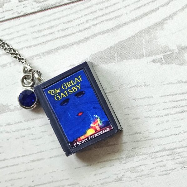Custom Miniature Book Necklace, Personalized Book Lover Gift, Bookish Jewelry 8 Send us the link, we'll make it tiny. Your favorite book cover, shrunk to charm-sized perfection and hung around your neck. This custom miniature book necklace is a personalized book lover gift — handmade bookish jewelry featuring a 3D printed mini book pendant with hand-gilded pages and an 18" stainless steel chain. ✦ Pendant size: .85" H × .75" W ✦ Construction: 100% handmade and 3D printed from an original SSC design — never mass produced ✦ Cover: Printed from your chosen image, laminated for (8)