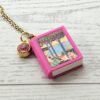 Custom Miniature Book Necklace, Personalized Book Lover Gift, Bookish Jewelry 6 Send us the link, we'll make it tiny. Your favorite book cover, shrunk to charm-sized perfection and hung around your neck. This custom miniature book necklace is a personalized book lover gift — handmade bookish jewelry featuring a 3D printed mini book pendant with hand-gilded pages and an 18" stainless steel chain. ✦ Pendant size: .85" H × .75" W ✦ Construction: 100% handmade and 3D printed from an original SSC design — never mass produced ✦ Cover: Printed from your chosen image, laminated for (6)