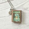 Custom Miniature Book Necklace, Personalized Book Lover Gift, Bookish Jewelry 7 Send us the link, we'll make it tiny. Your favorite book cover, shrunk to charm-sized perfection and hung around your neck. This custom miniature book necklace is a personalized book lover gift — handmade bookish jewelry featuring a 3D printed mini book pendant with hand-gilded pages and an 18" stainless steel chain. ✦ Pendant size: .85" H × .75" W ✦ Construction: 100% handmade and 3D printed from an original SSC design — never mass produced ✦ Cover: Printed from your chosen image, laminated for (7)