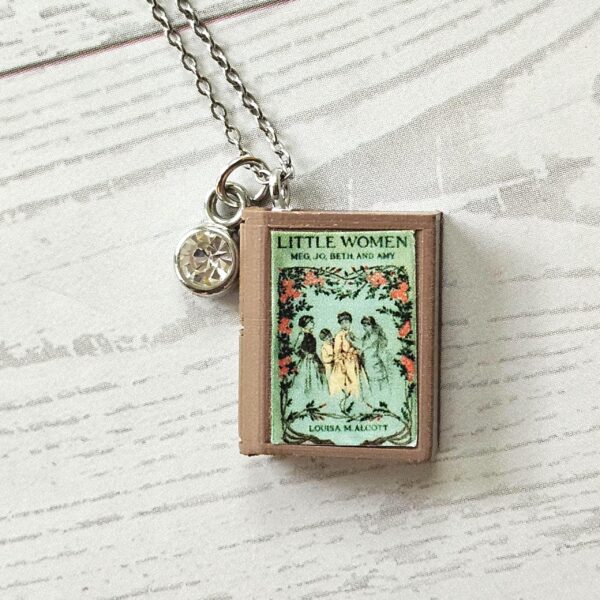 Custom Miniature Book Necklace, Personalized Book Lover Gift, Bookish Jewelry 7 Send us the link, we'll make it tiny. Your favorite book cover, shrunk to charm-sized perfection and hung around your neck. This custom miniature book necklace is a personalized book lover gift — handmade bookish jewelry featuring a 3D printed mini book pendant with hand-gilded pages and an 18" stainless steel chain. ✦ Pendant size: .85" H × .75" W ✦ Construction: 100% handmade and 3D printed from an original SSC design — never mass produced ✦ Cover: Printed from your chosen image, laminated for (7)