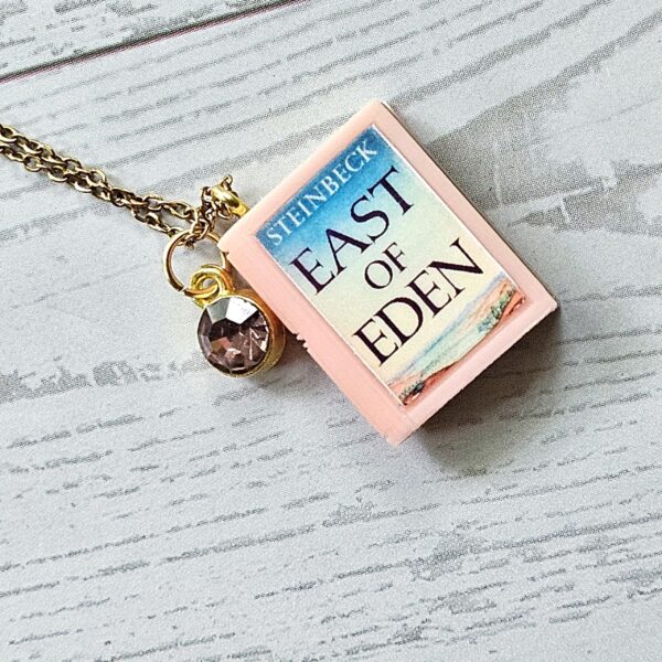 Custom Miniature Book Necklace, Personalized Book Lover Gift, Bookish Jewelry 10 Send us the link, we'll make it tiny. Your favorite book cover, shrunk to charm-sized perfection and hung around your neck. This custom miniature book necklace is a personalized book lover gift — handmade bookish jewelry featuring a 3D printed mini book pendant with hand-gilded pages and an 18" stainless steel chain. ✦ Pendant size: .85" H × .75" W ✦ Construction: 100% handmade and 3D printed from an original SSC design — never mass produced ✦ Cover: Printed from your chosen image, laminated for (10)